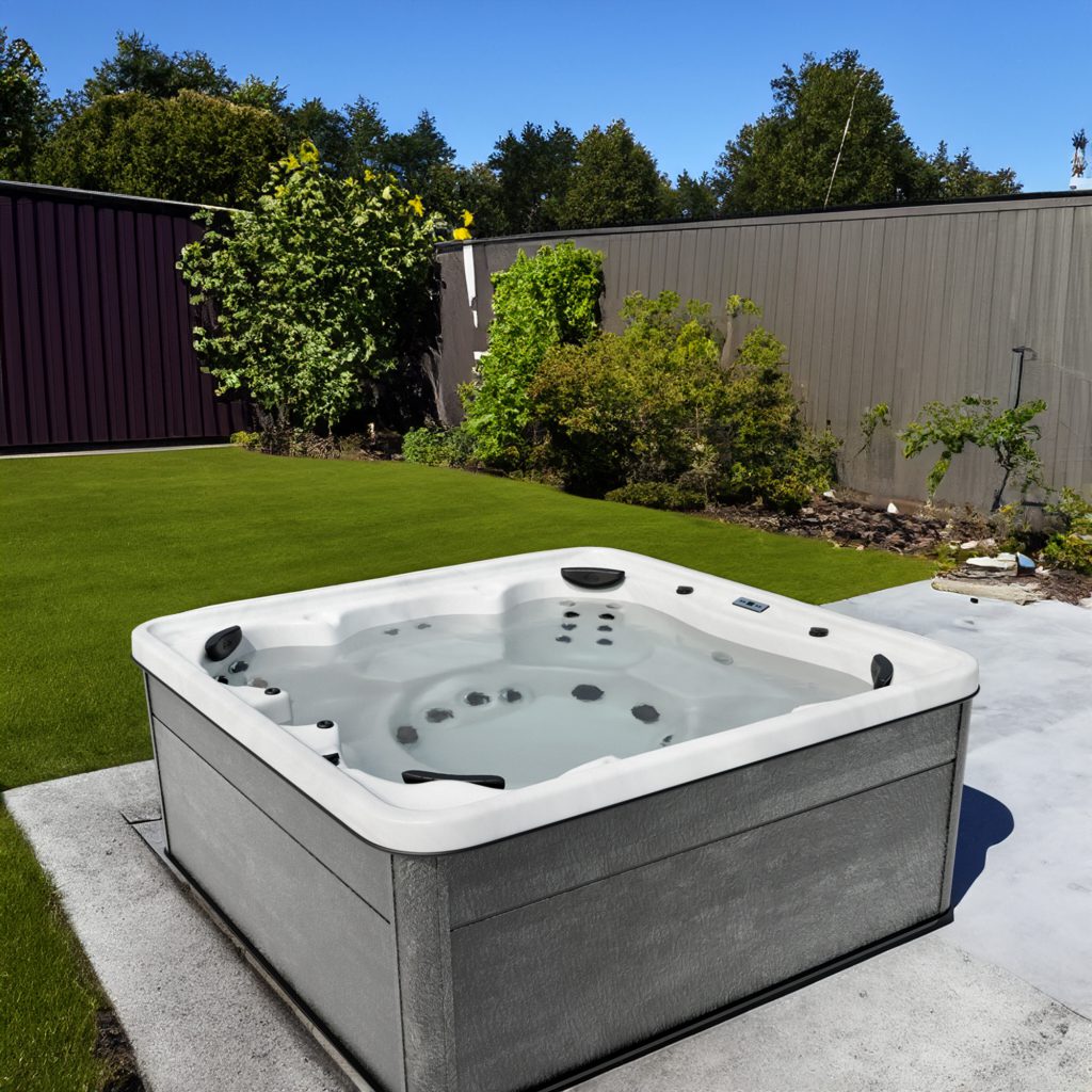 Modern outdoor hot tub installed on patio beside landscaped backyard lawn.