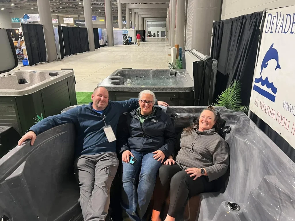 DeVader’s staff seated in hot tub display at trade show booth.