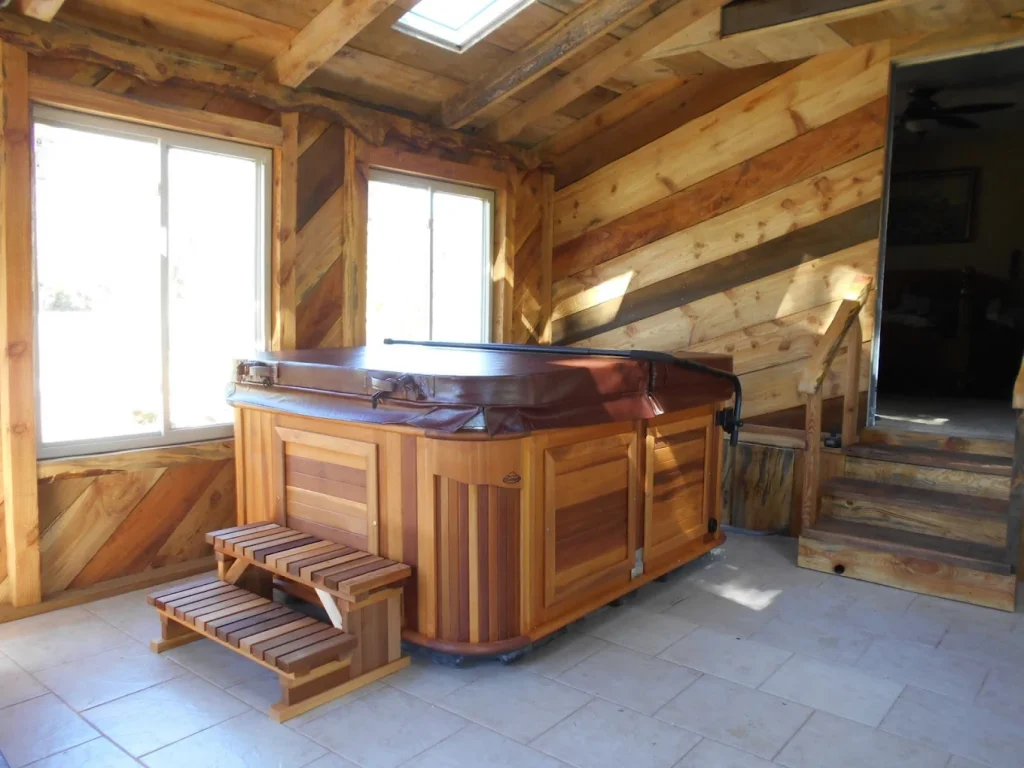 Indoor hot tub with closed cover inside rustic wood-paneled room.