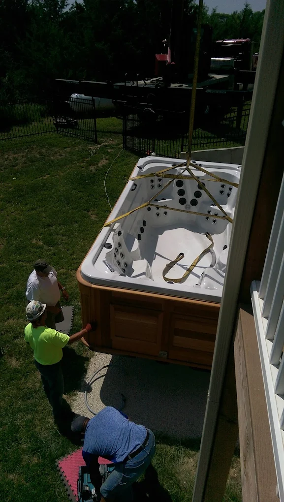 Hot tub being lowered by crane during backyard installation.
