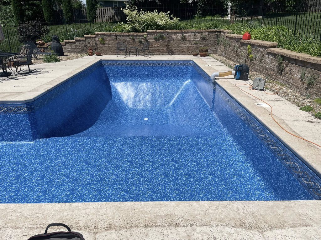 Empty in-ground pool with new blue liner during installation process.